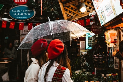 一个戴着红色针织帽和白色夹克的女人，手里拿着伞